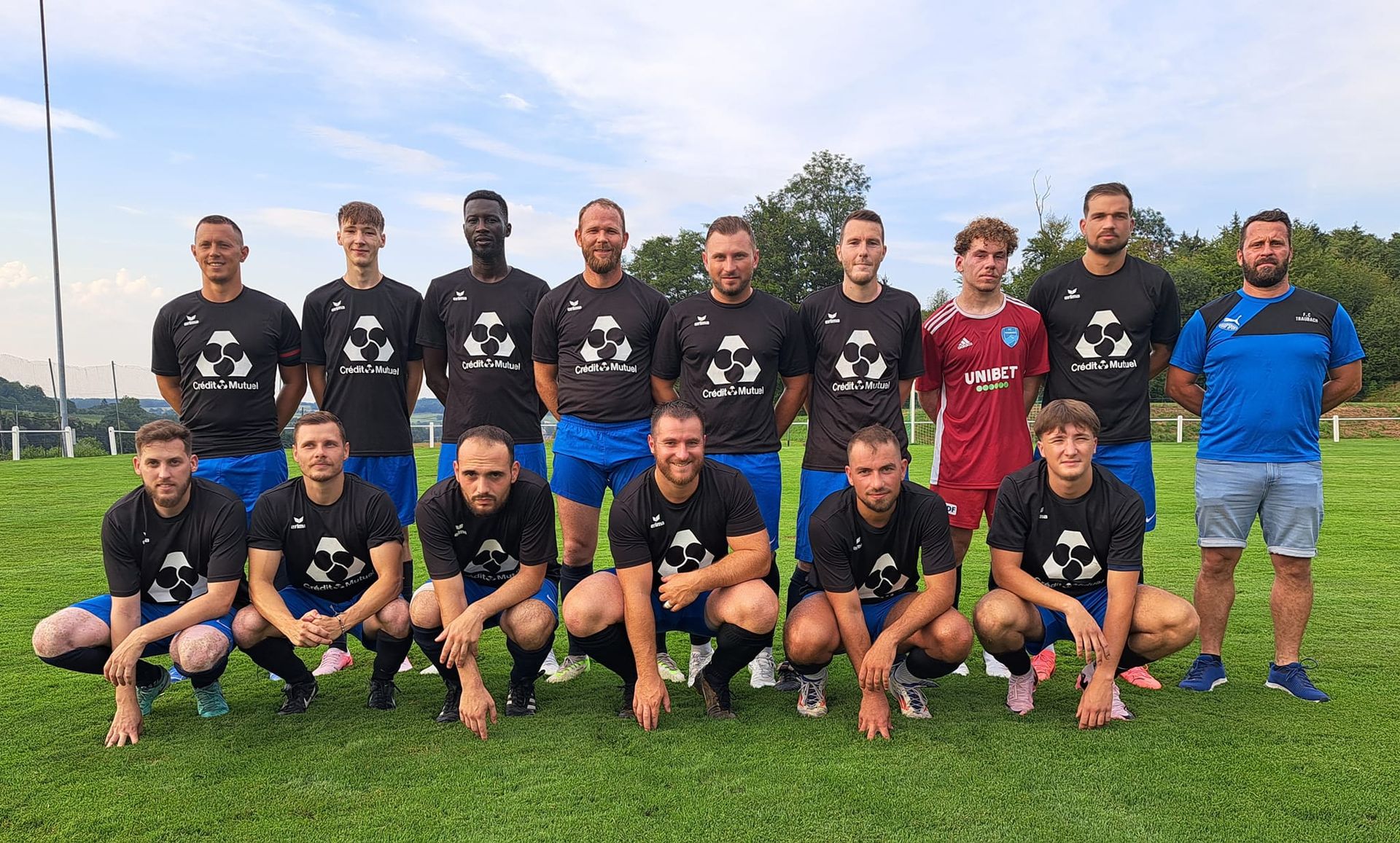 Un groupe d'hommes pose pour une photo sur un terrain de football.