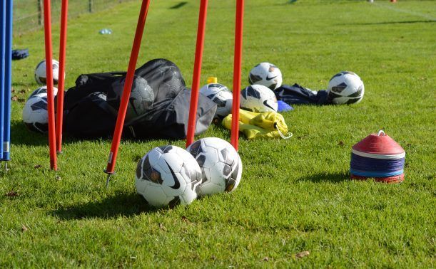 Un tas de ballons de football sont posés sur l'herbe