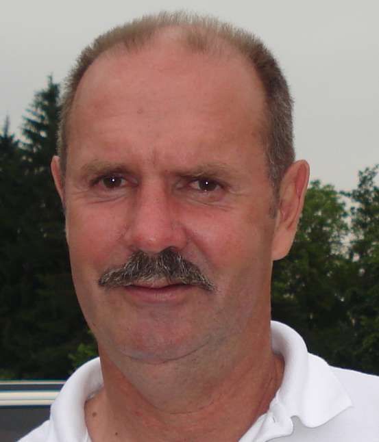 Un homme avec une moustache porte une chemise blanche.