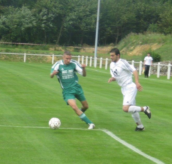 Un joueur de football portant un maillot vert sur lequel est écrit « MC »