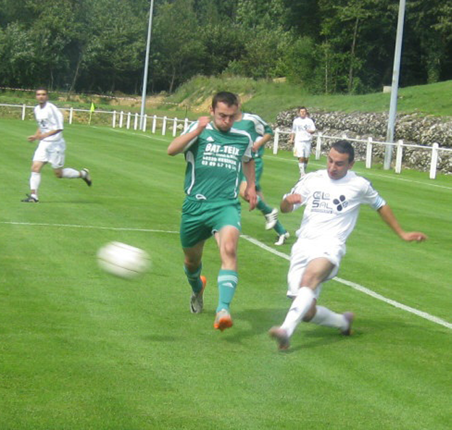 Un joueur de football portant un maillot vert sur lequel est écrit