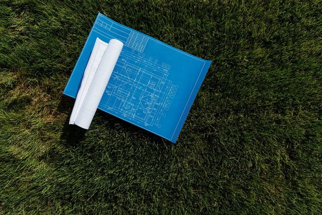 Blue notebook with rolled white papers lying on grass