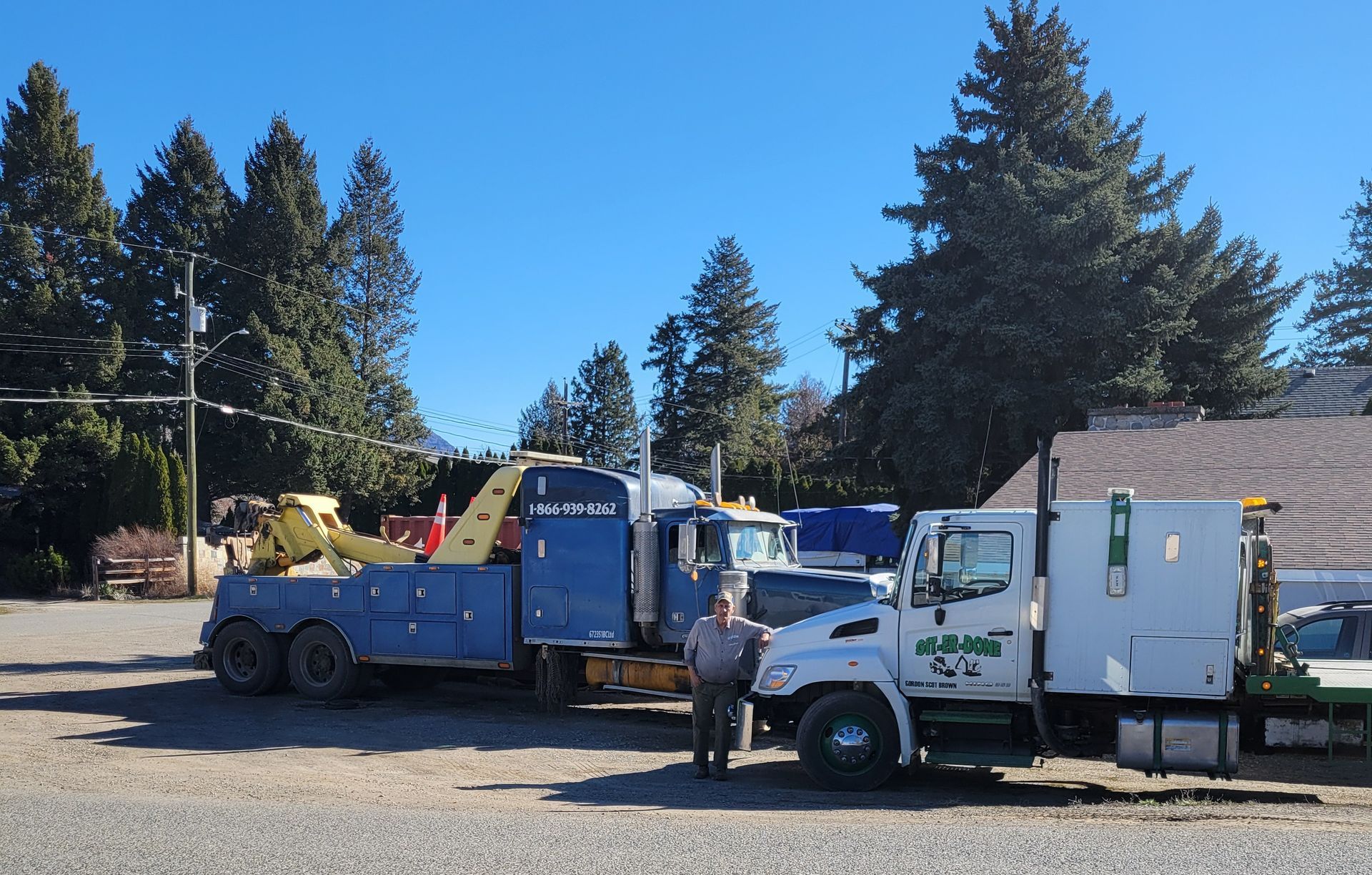 A man stands in front of a tow truck that says Git-Er-Done on the side