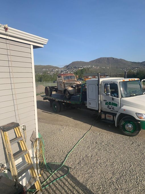 White tow tuck removing scrap vehicle from property in Kamloops