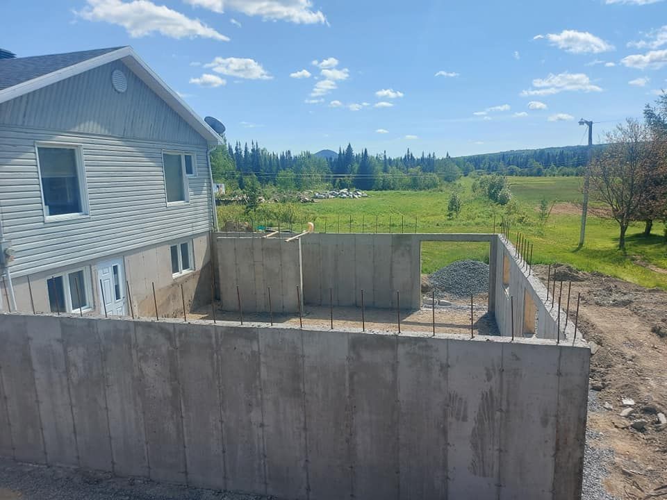 Une maison en construction avec un mur en béton devant.
