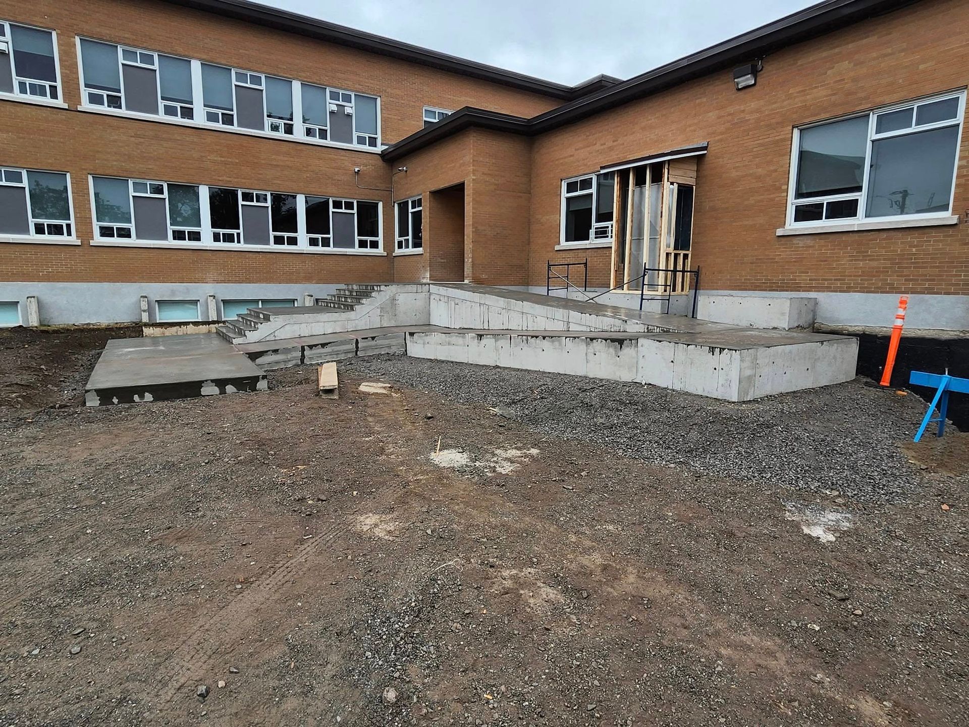 Un grand bâtiment en briques avec des escaliers menant à celui-ci est en construction.