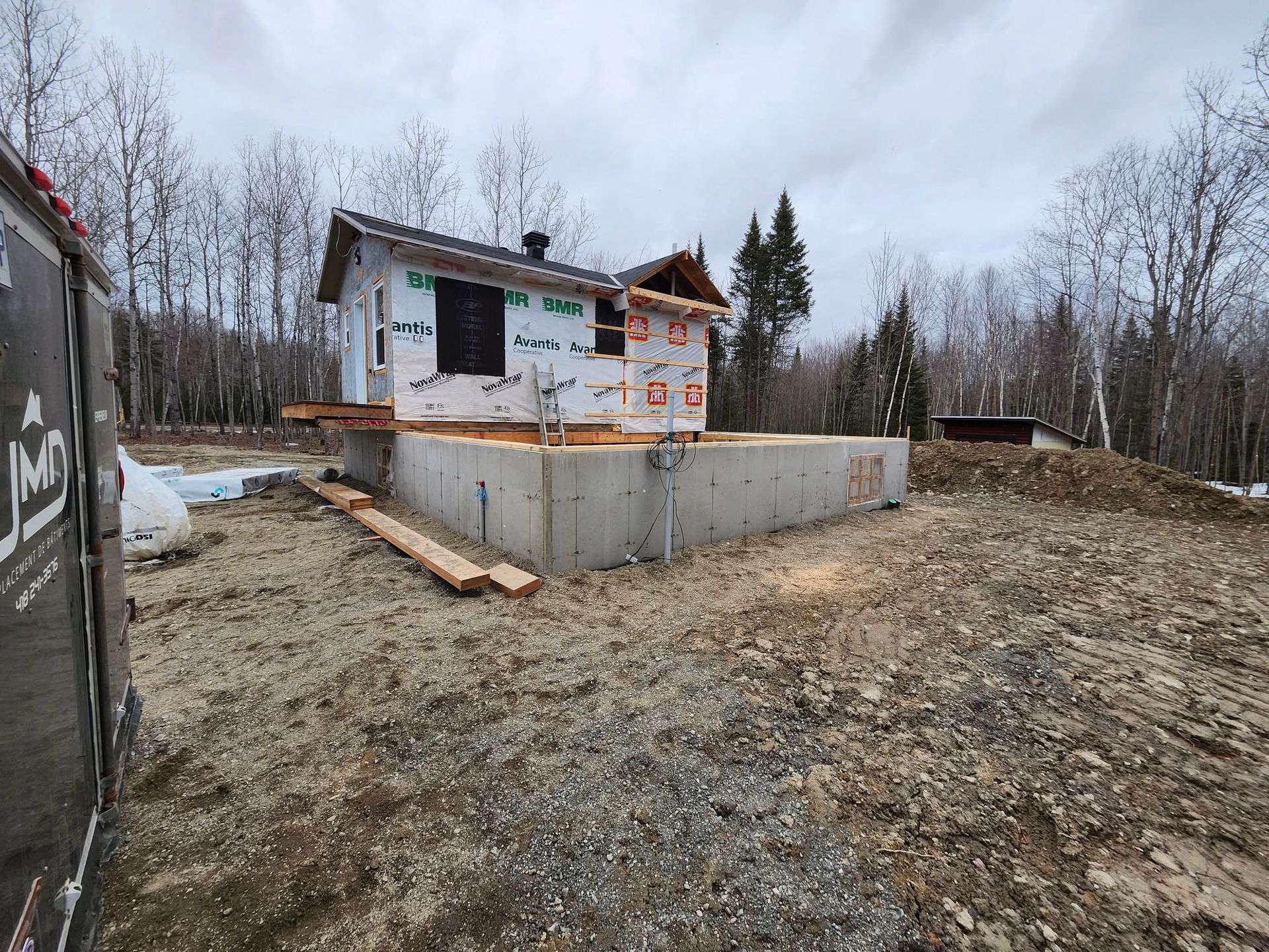 Une petite maison est en construction au milieu d'un champ de terre.
