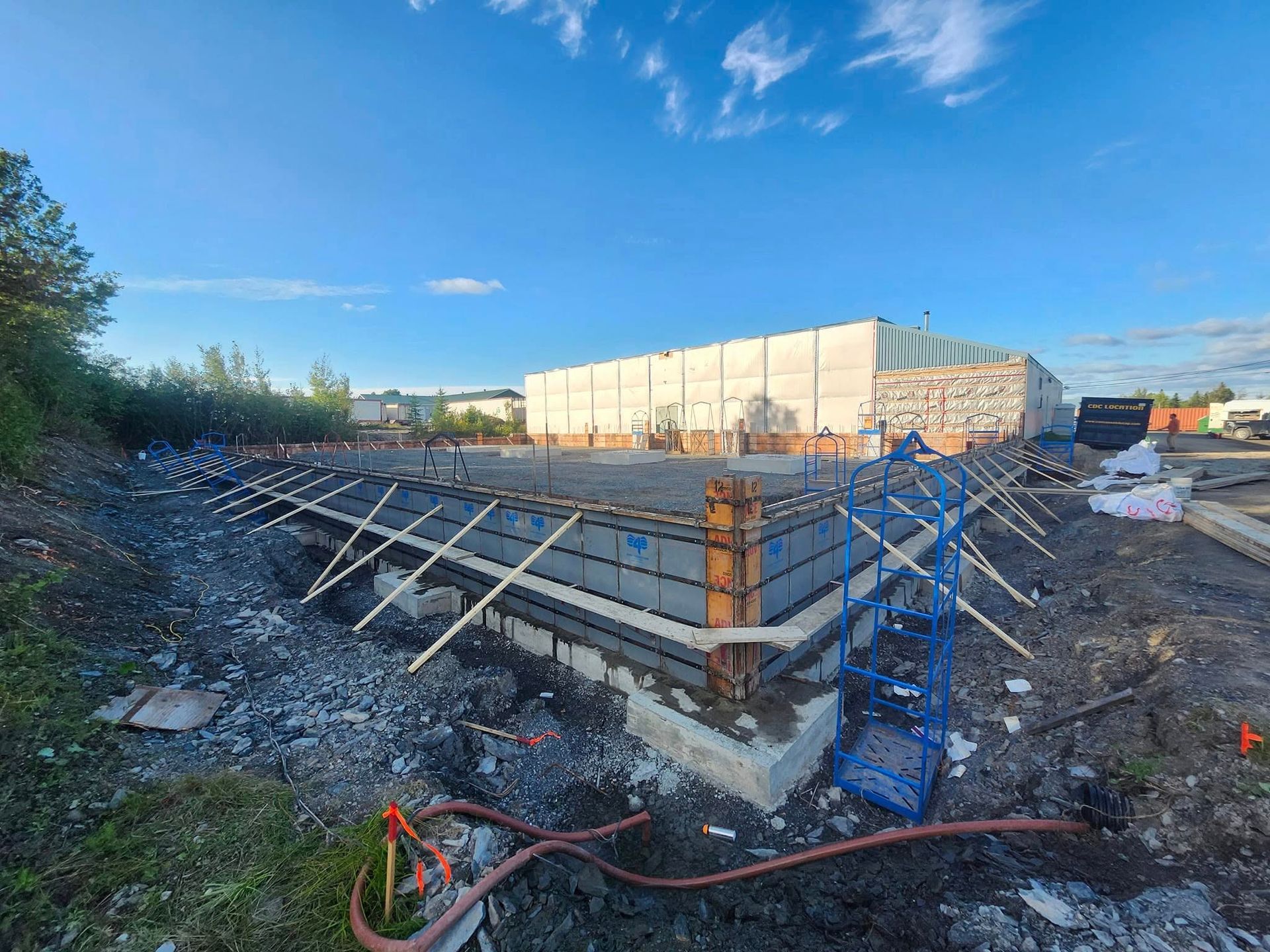 Un grand bâtiment est en construction au milieu d'un champ de terre.