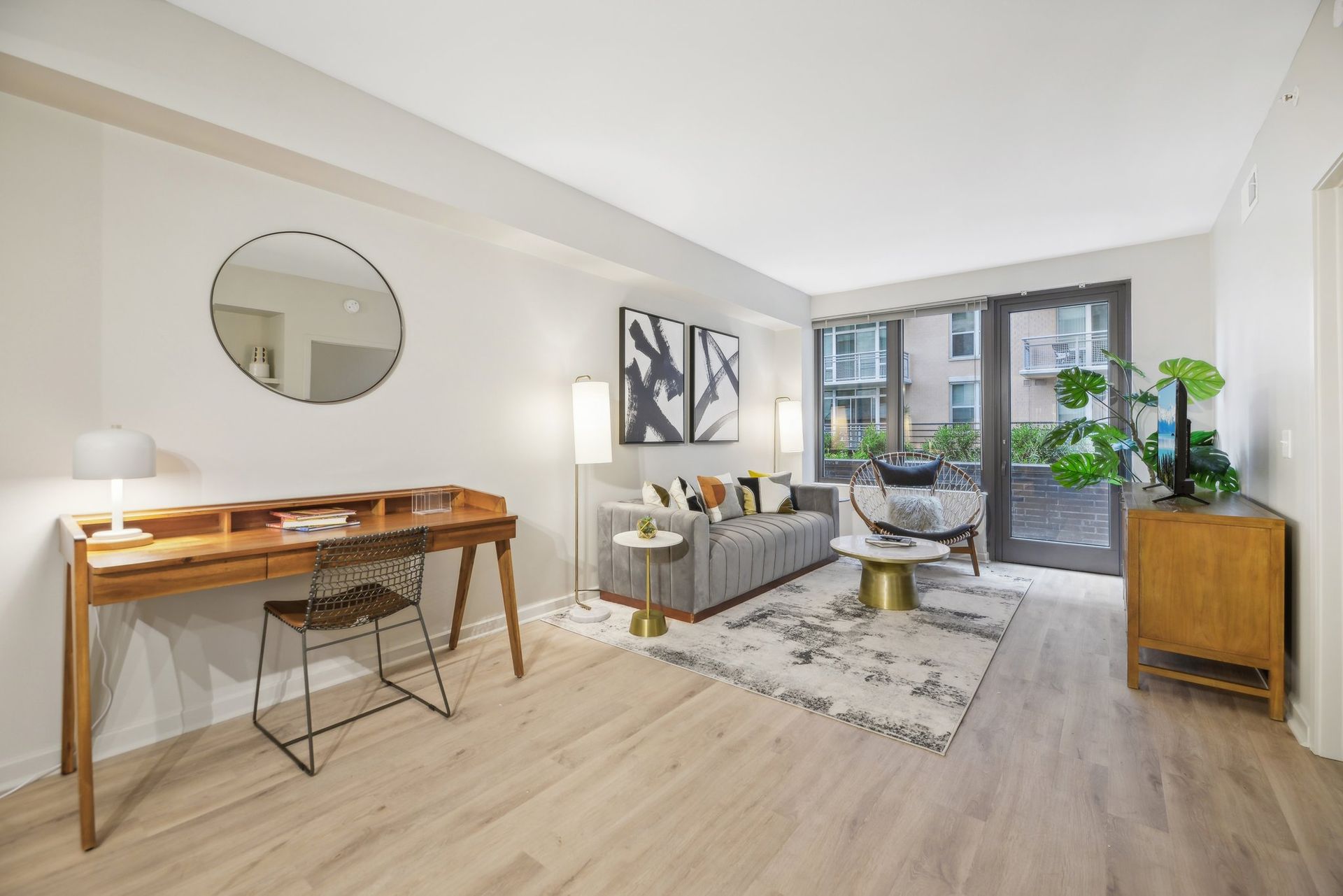 A living room with a couch, desk, chair, and mirror at Solaire 8200 Dixon offers apartments in Silver Spring, MD.