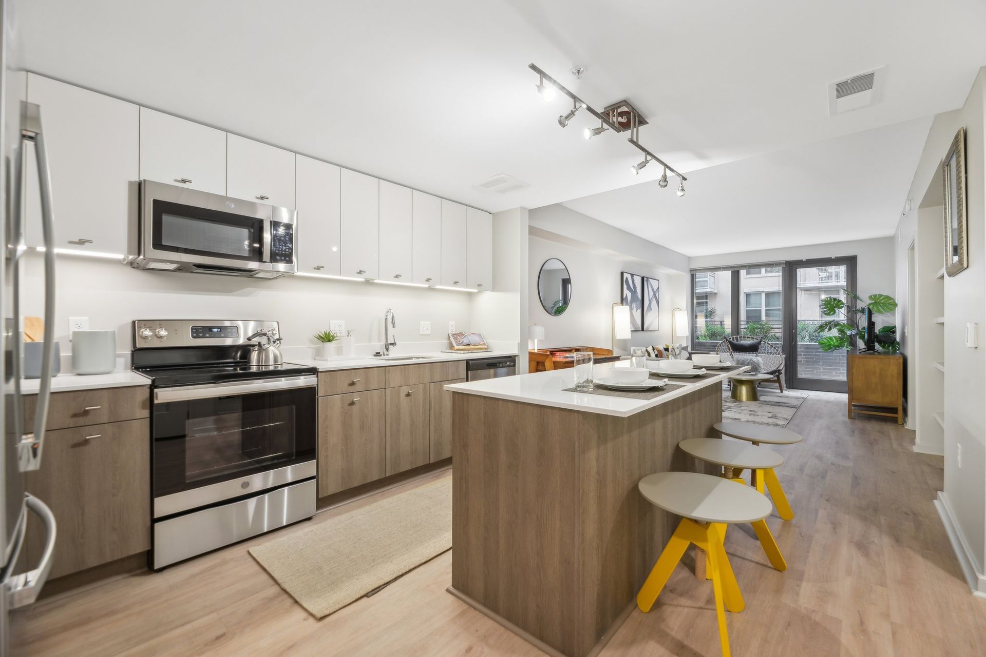 A kitchen with stainless steel appliances, wooden cabinets, and a large island at Solaire 8200 Dixon offers apartments in Silver Spring, MD.