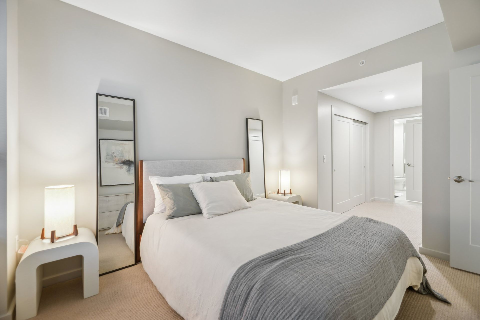 A bedroom with a large bed and two mirrors at Solaire 8200 Dixon offers apartments in Silver Spring, MD.