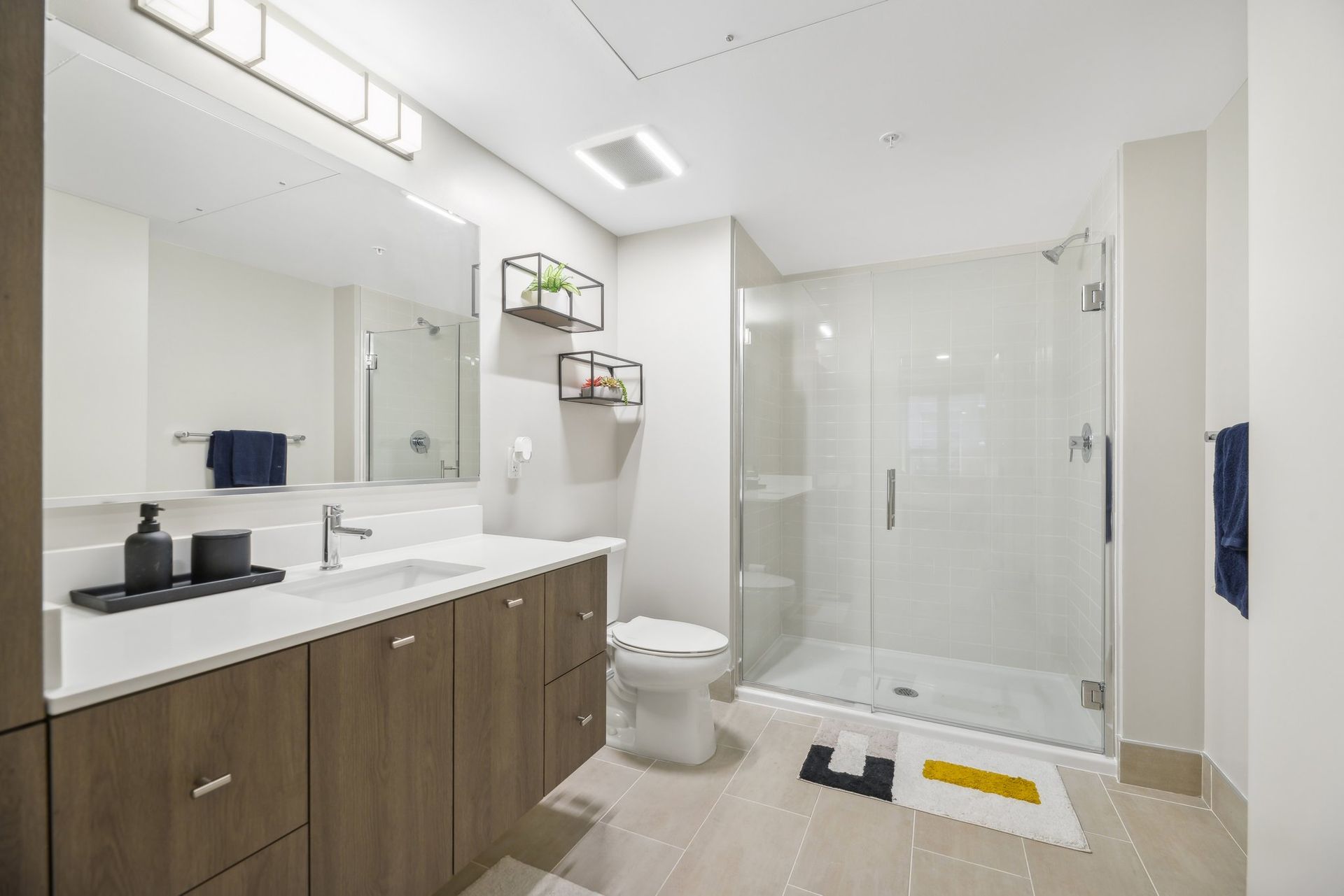 A bathroom with a toilet, sink, mirror and walk-in shower at Solaire 8200 Dixon offers apartments in Silver Spring, MD.