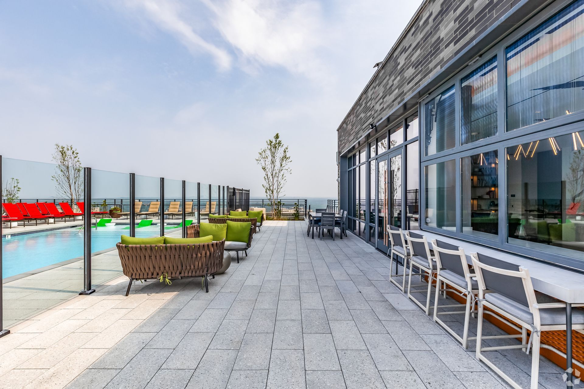 A patio with chairs, tables, and a pool in the background at Solaire 8200 Dixon offers high-rise apartments for rent in Silver Spring, MD.