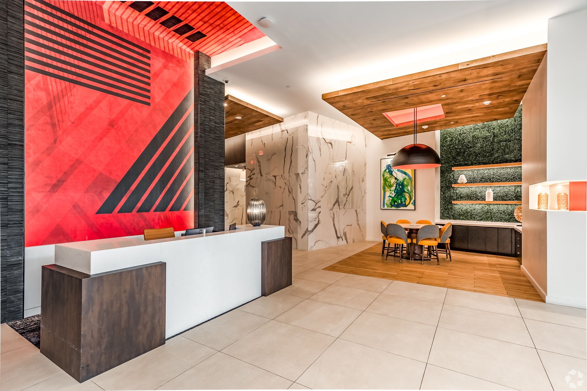 A lobby with a red wall and a white counter.