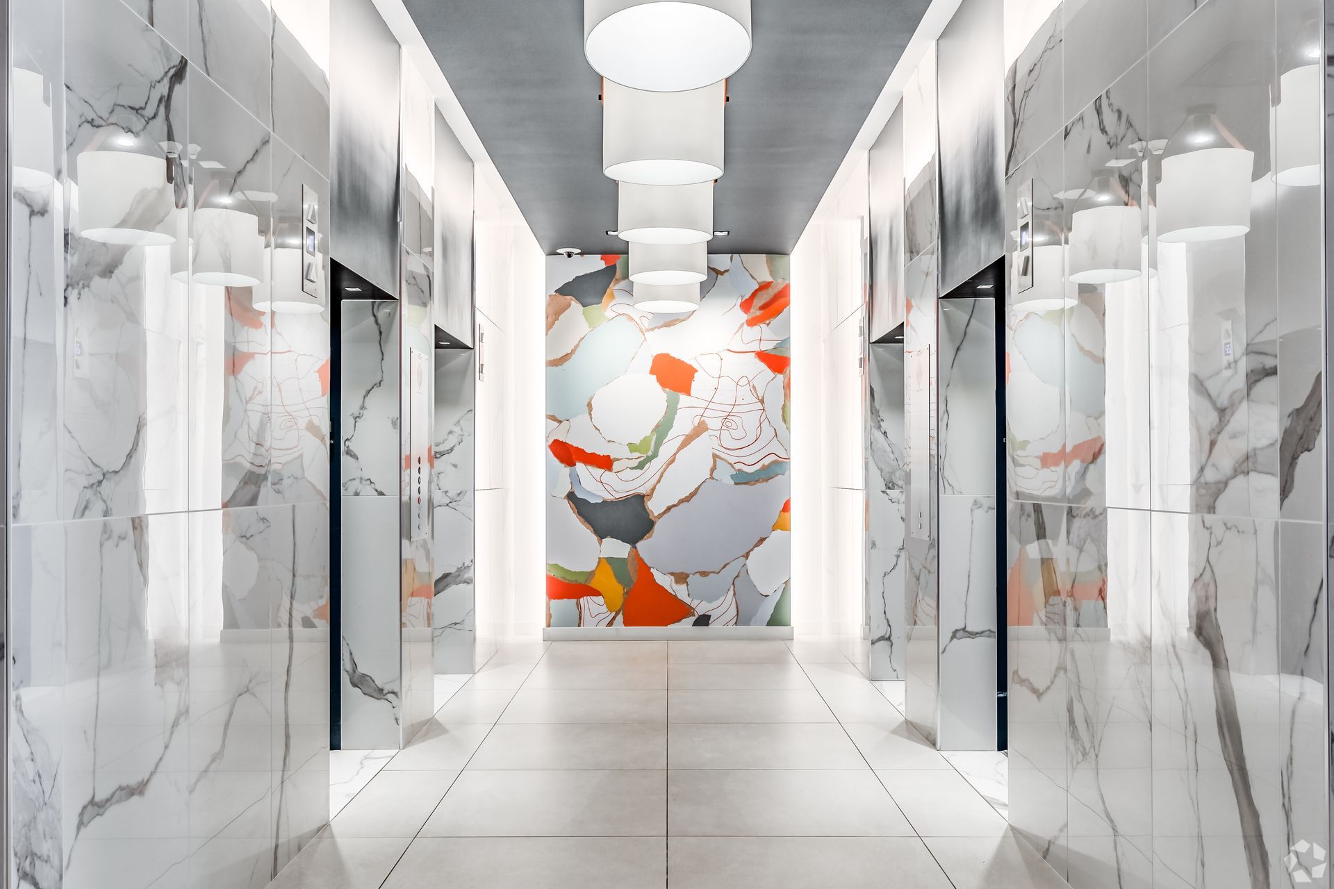 A long hallway with marble walls and a large painting on the wall.