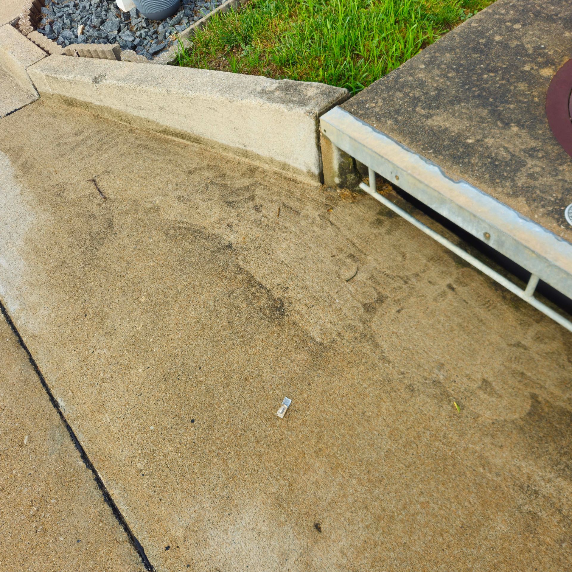 White house siding with green mildew staining above a stone foundation beside a lawn