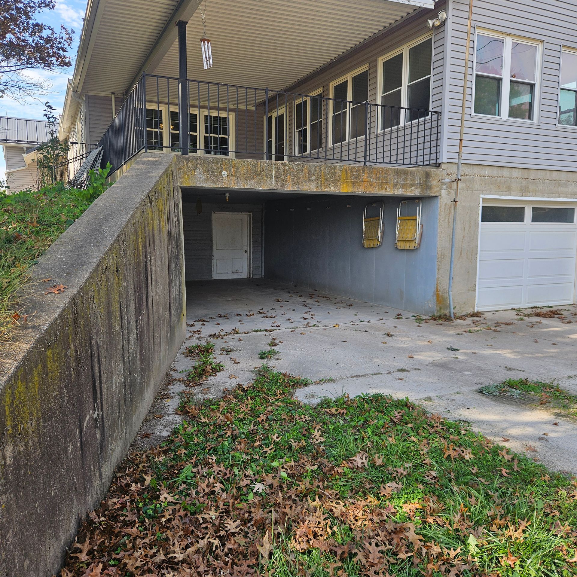 Suburban house with gray siding, attached garage, and a wide driveway in a wooded yard