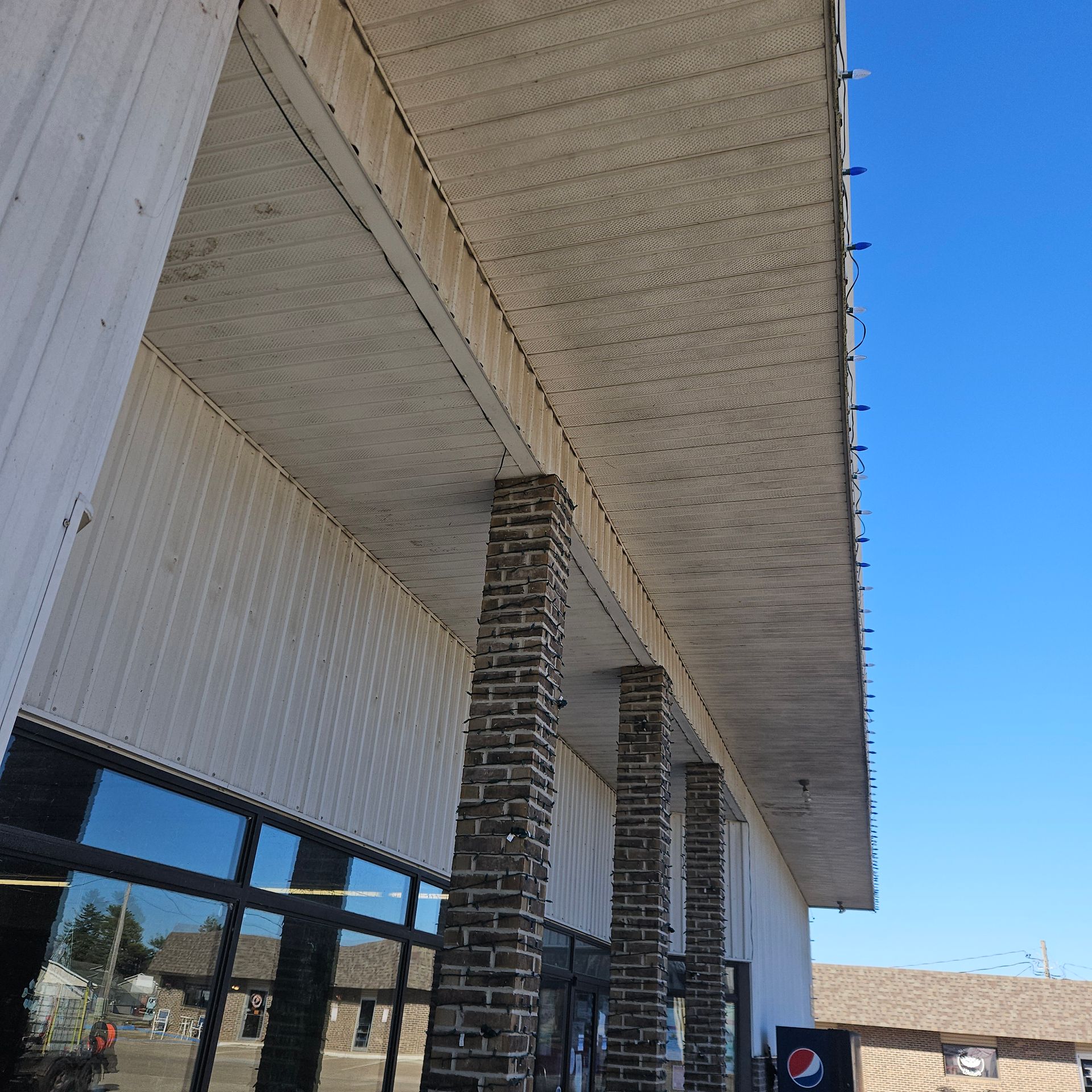 White house siding with heavy green mildew and weather staining on the side wall under a blue sky
