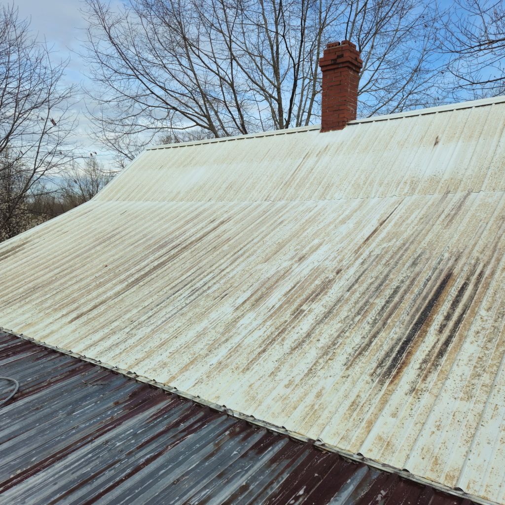 Rusty corrugated metal roof with a brick chimney under a clear blue sky