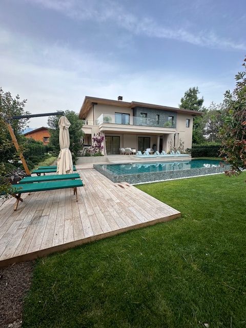 Casa moderna a due piani con piscina, patio e prato verde al crepuscolo.