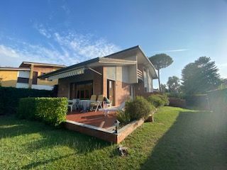 Casa moderna con portico anteriore, prato e siepe, immersa nella luce del giorno.