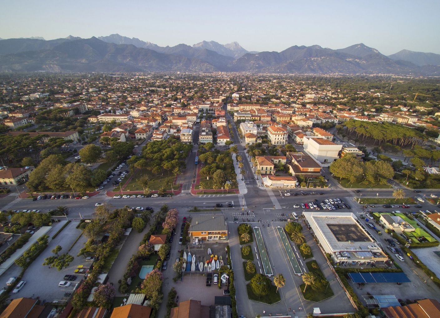 Veduta aerea di una città al crepuscolo, con strade, edifici e montagne sullo sfondo.