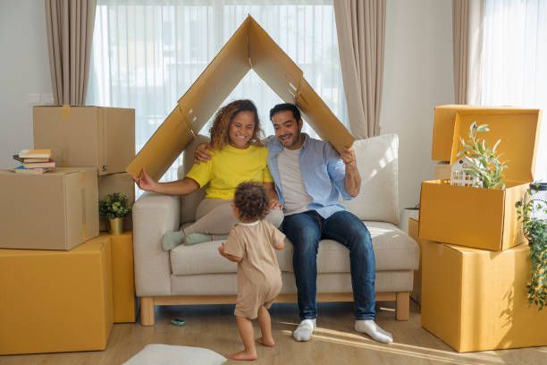 A family is sitting on a couch under a cardboard house.