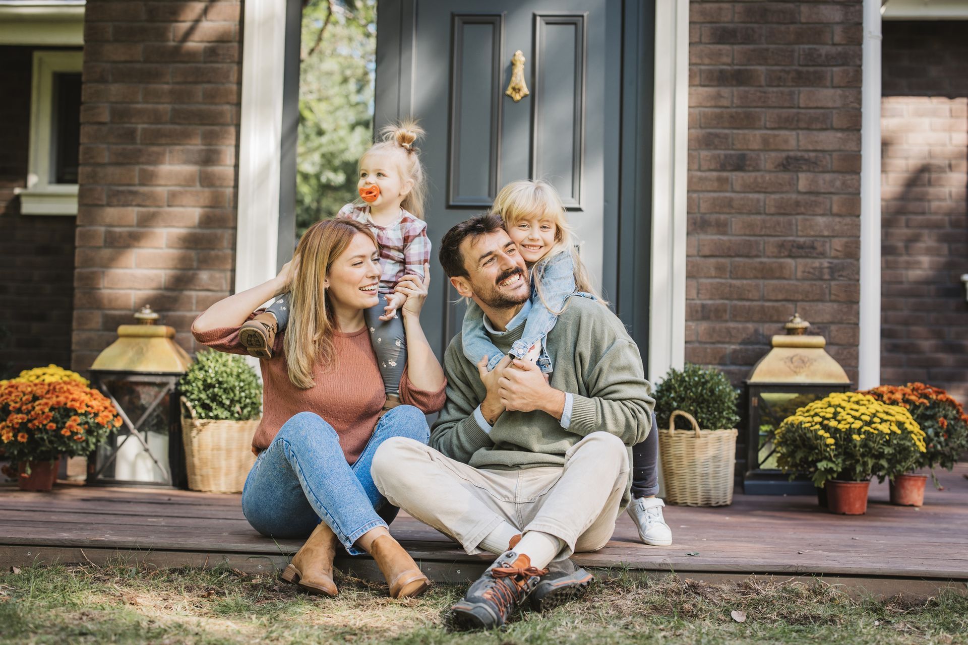 A family is sitting on the porch of their house.