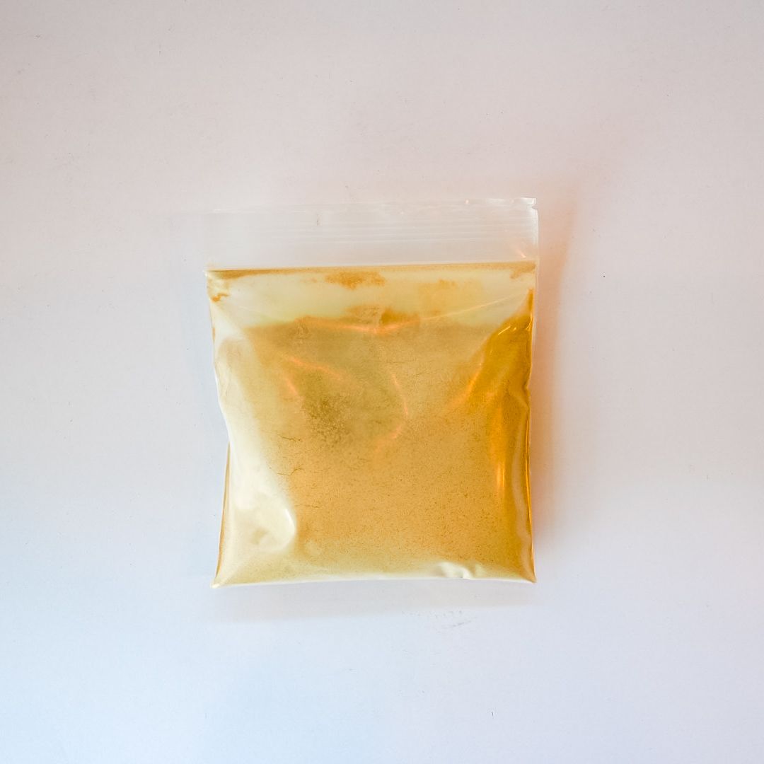 Small clear plastic packet filled with yellow powder on a white background
