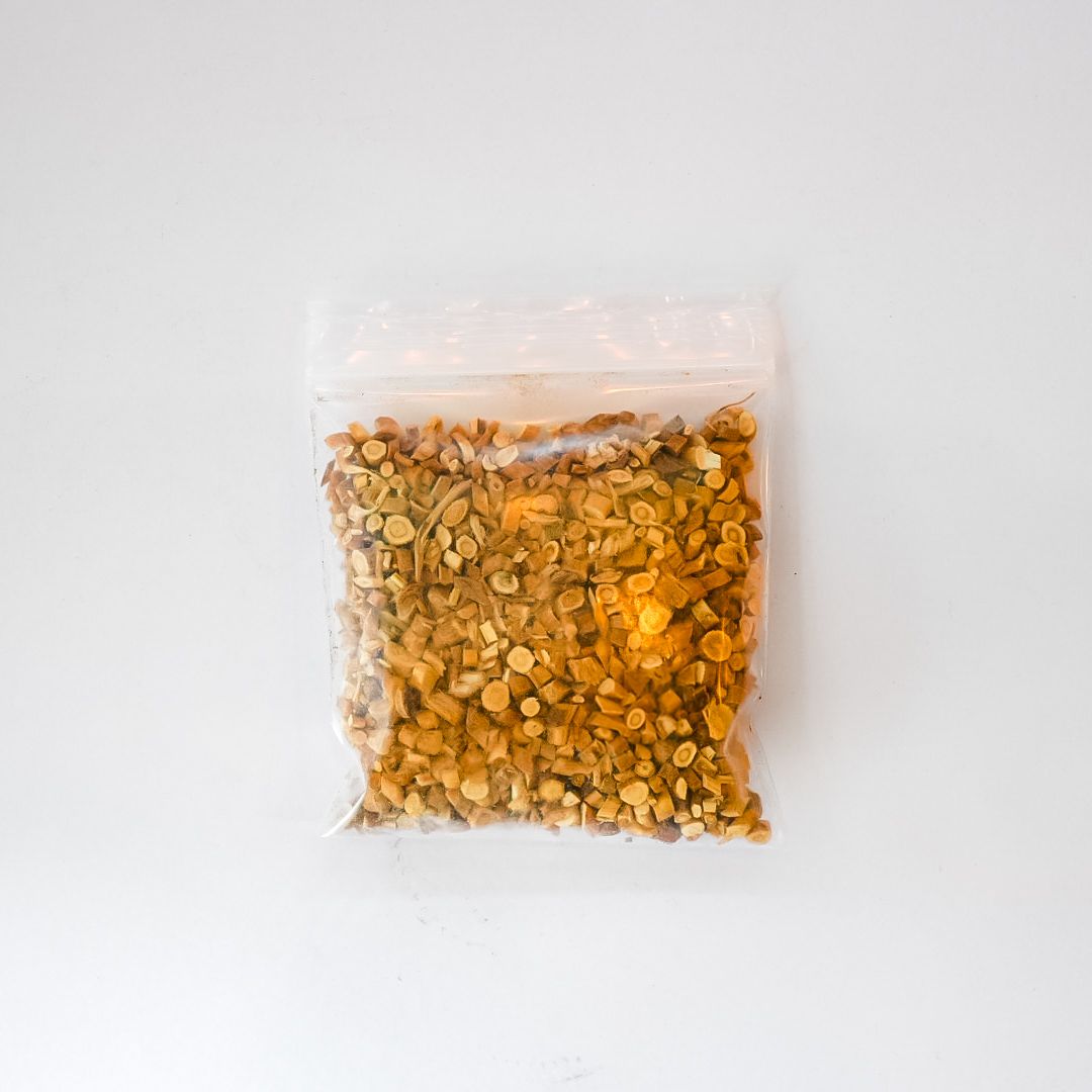 Clear plastic bag of dried astragalus root with a bright yellow label on a white background