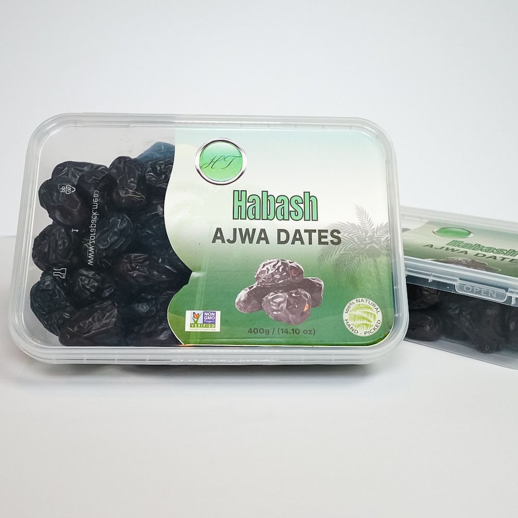 Plastic container of black Ajwa dates with green “Hafash AJWA DATES” label