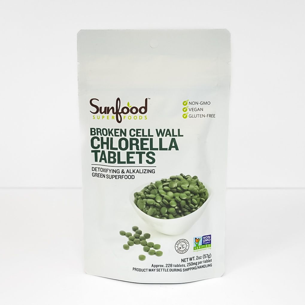 White pouch of Sunfood broken cell wall chlorella tablets with green tablet bowl on the front.
