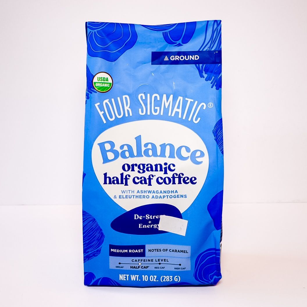 Blue bag of Four Sigmatic Balance organic half coffee with a white label on a plain background