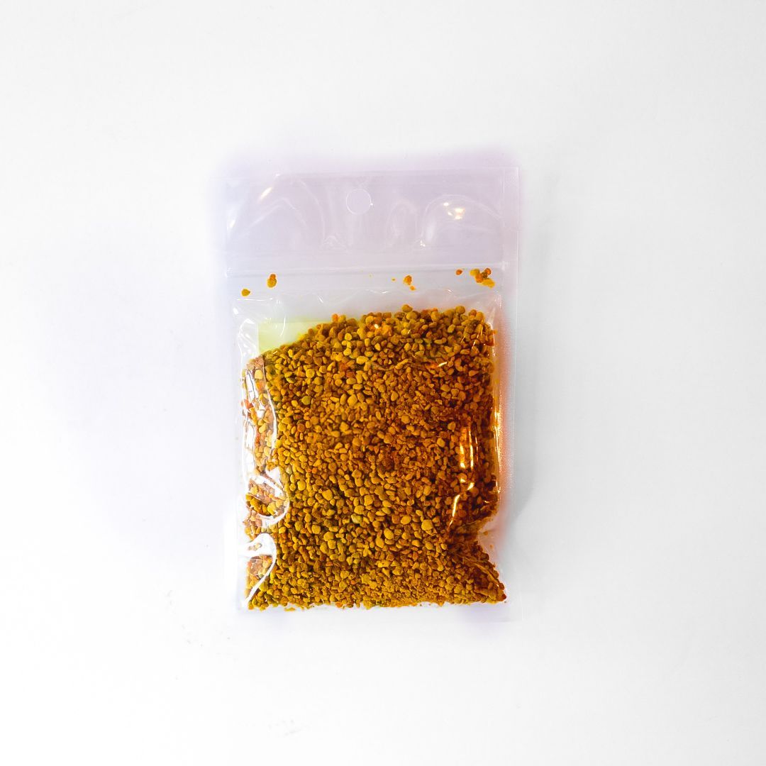 Clear plastic bag of yellow bee pollen granules with a bright green label on a white background