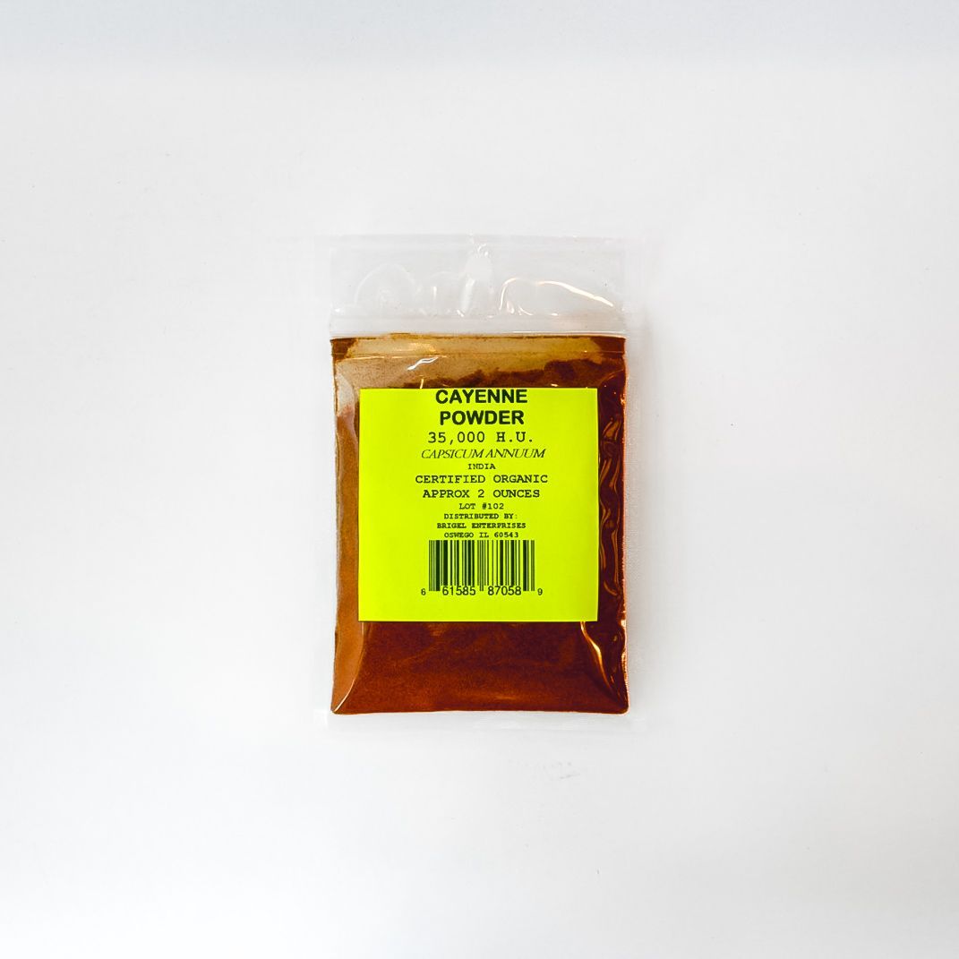 Small clear plastic bag of reddish-brown spice with a bright yellow label on a white background