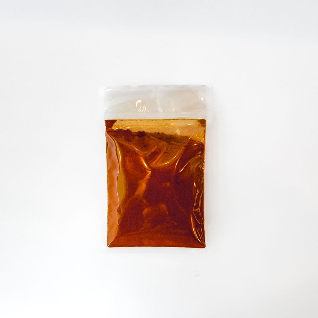 Small clear plastic bag of reddish-brown spice with a bright yellow label on a white background