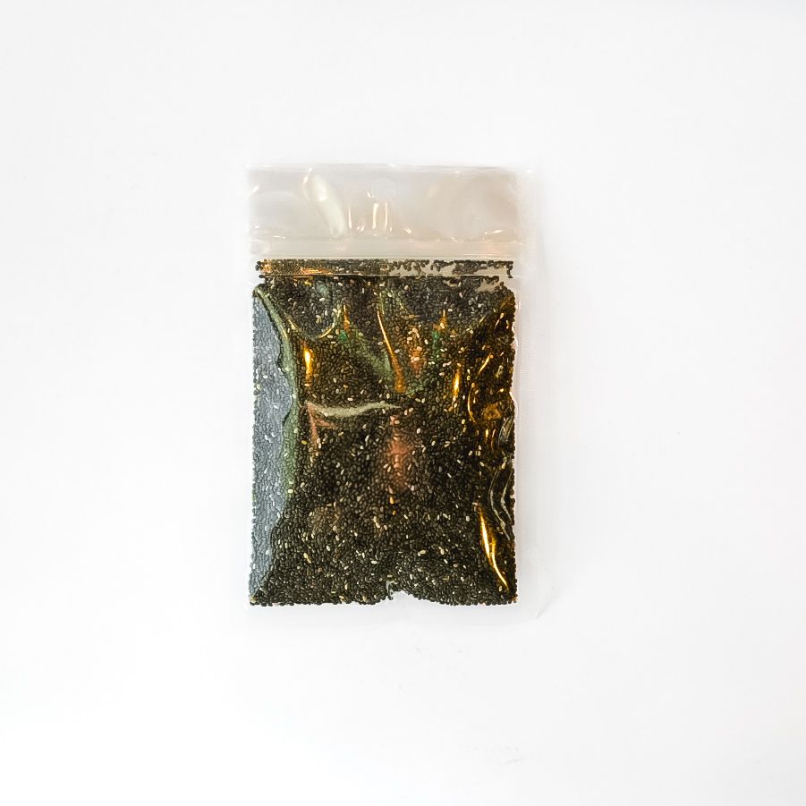 Small clear plastic bag of black chia seeds with a bright yellow label on a white background