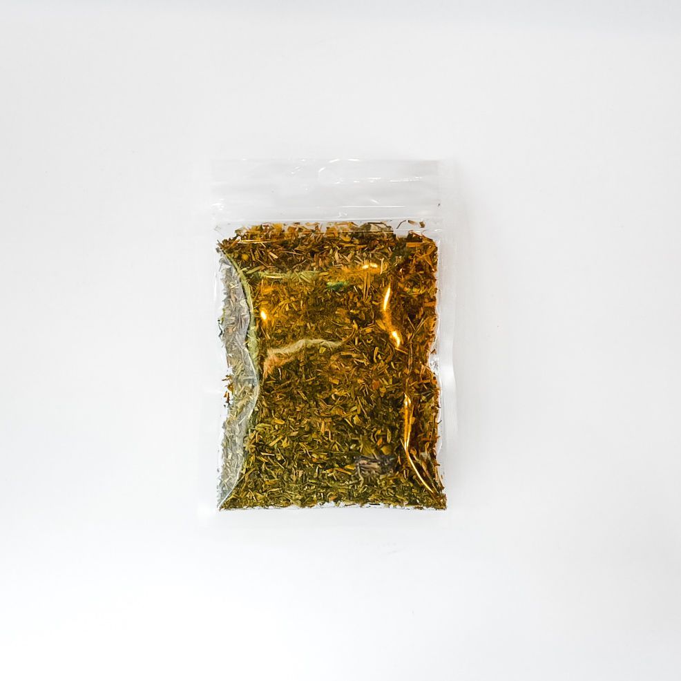 Clear plastic bag of dried herbs or tea with a bright yellow label on a white background