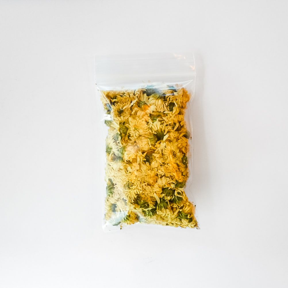Small clear plastic bag of dried herbs with a bright yellow label and barcode on a white background
