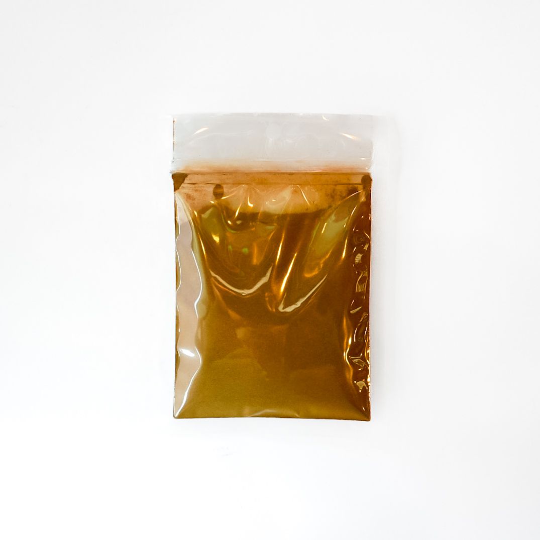 Small clear plastic bag filled with amber liquid and a bright yellow label, on a white background