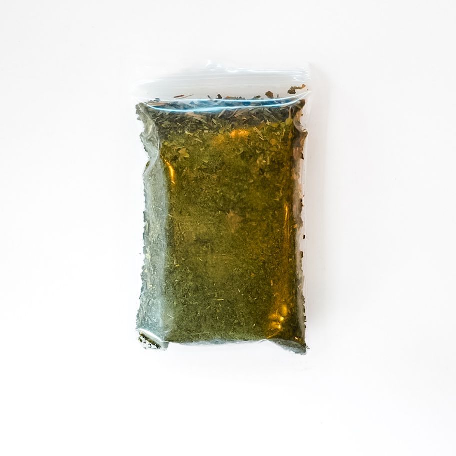 Clear bag of loose tea leaves with a bright yellow label on a white background
