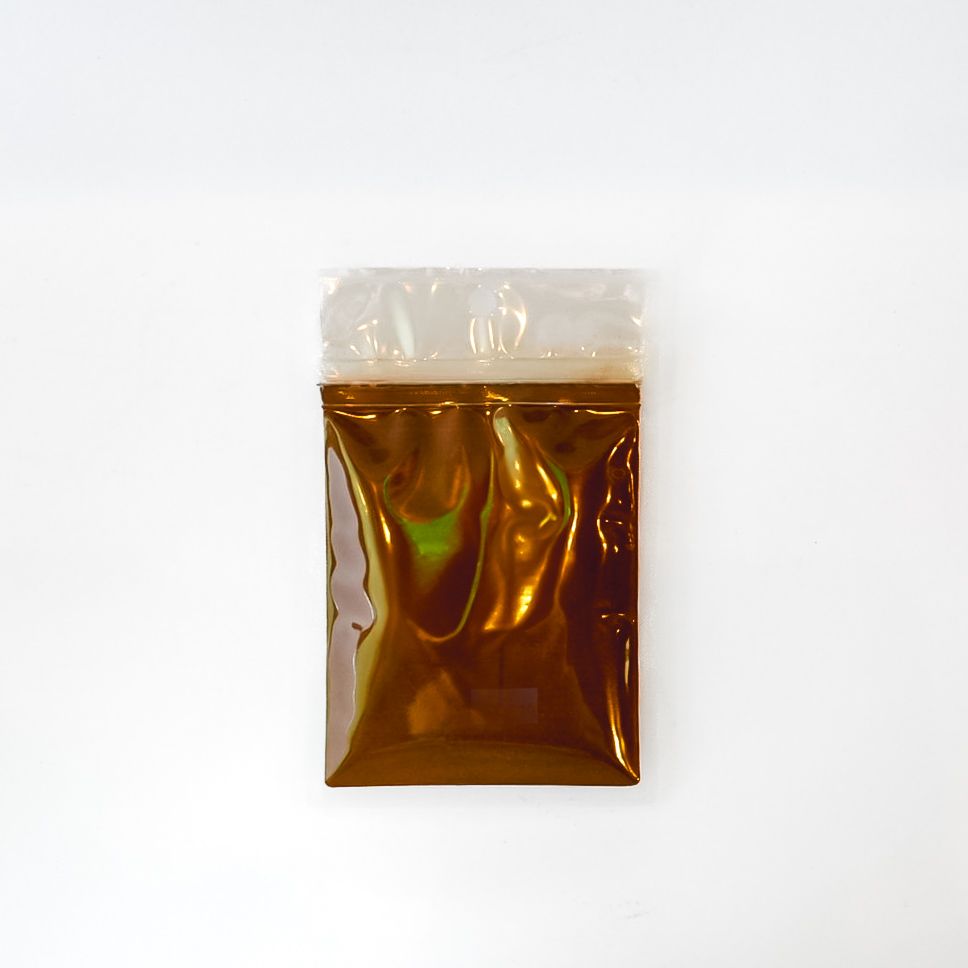 Small clear plastic bag with amber liquid and a bright yellow label on a white background
