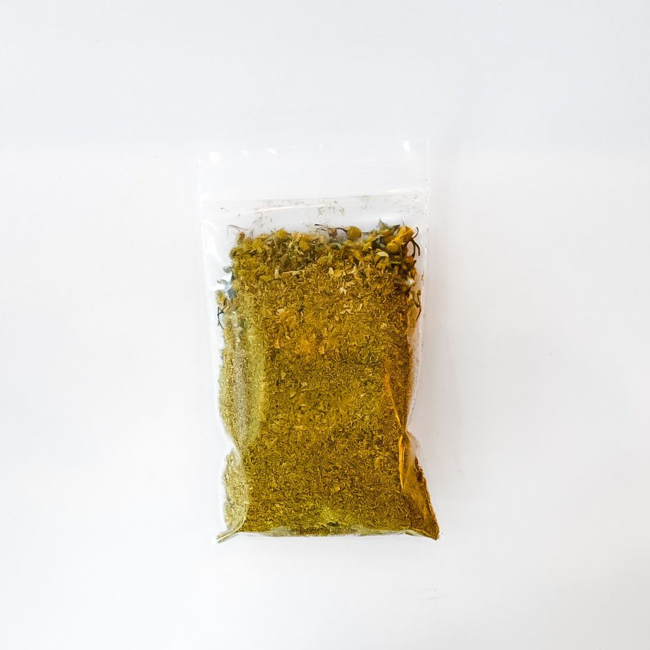 Clear bag of chamomile flowers with bright yellow label on a white background