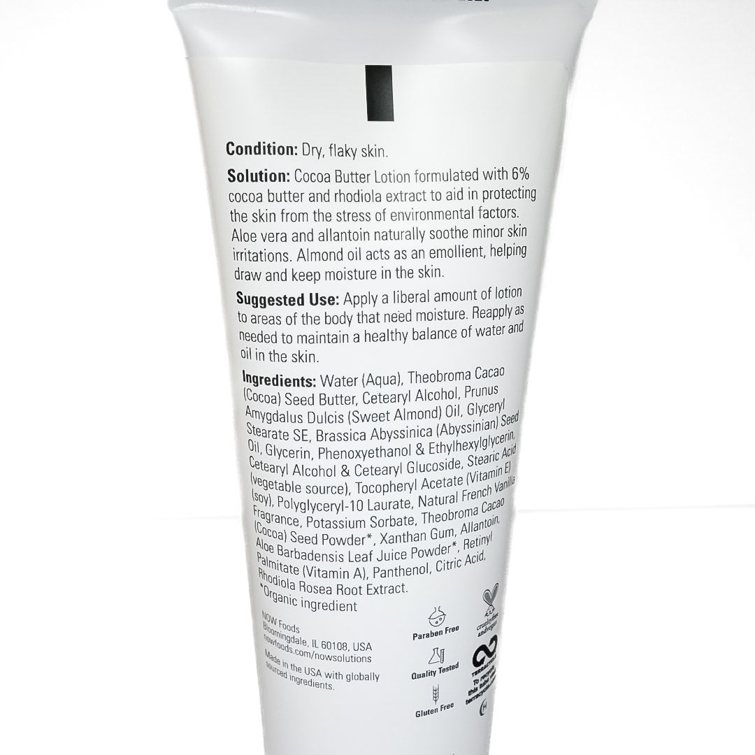 White cosmetic tube with green leaf and brown cacao pod label on a plain background