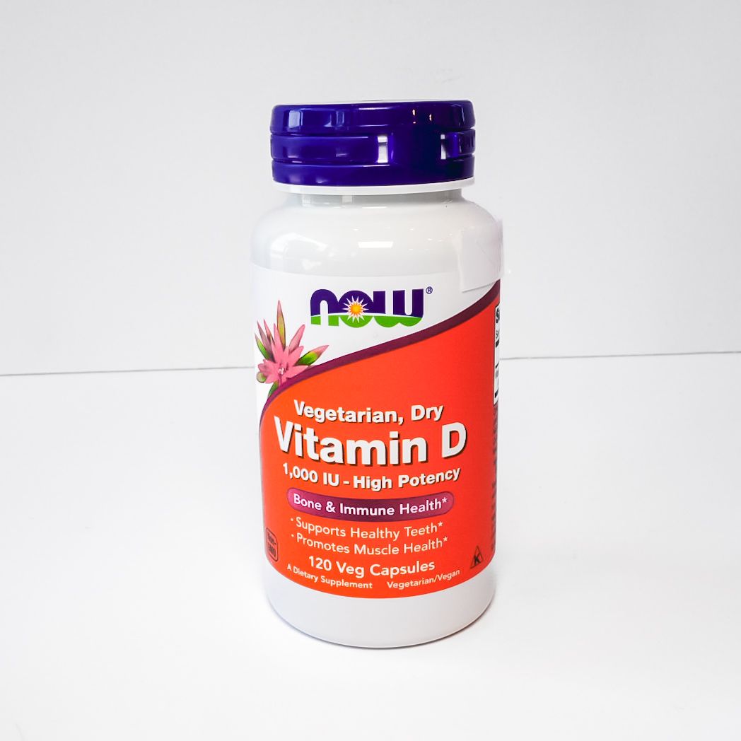 NOW Vitamin D-3 supplement bottle with white body and purple cap on a plain background