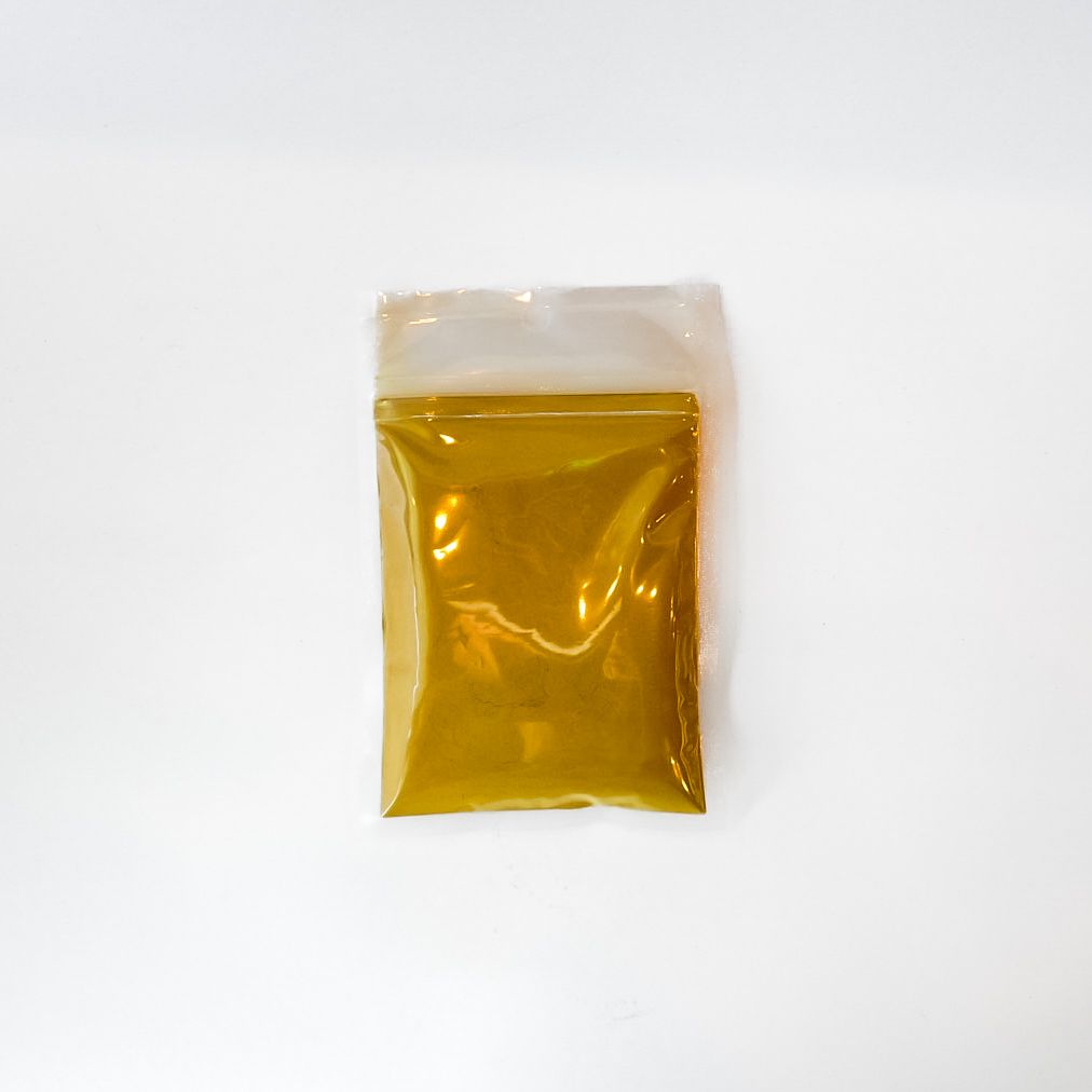 Small clear plastic bag of yellow powder with a bright green label on a white background