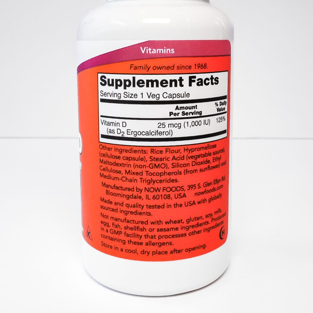 NOW Vitamin D-3 supplement bottle with white body and purple cap on a plain background