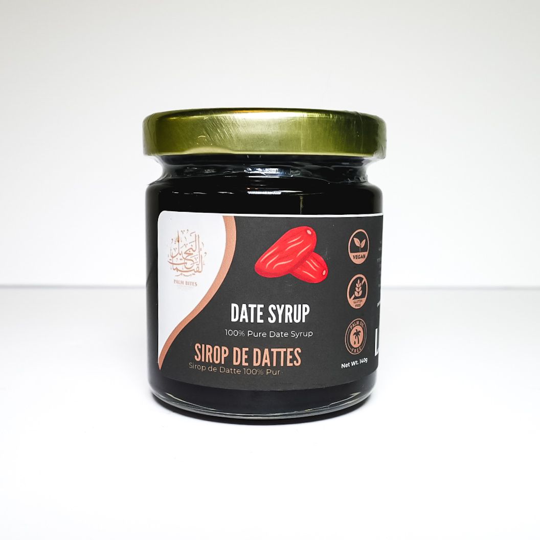 Jar of date syrup with a gold lid and black label on a white background