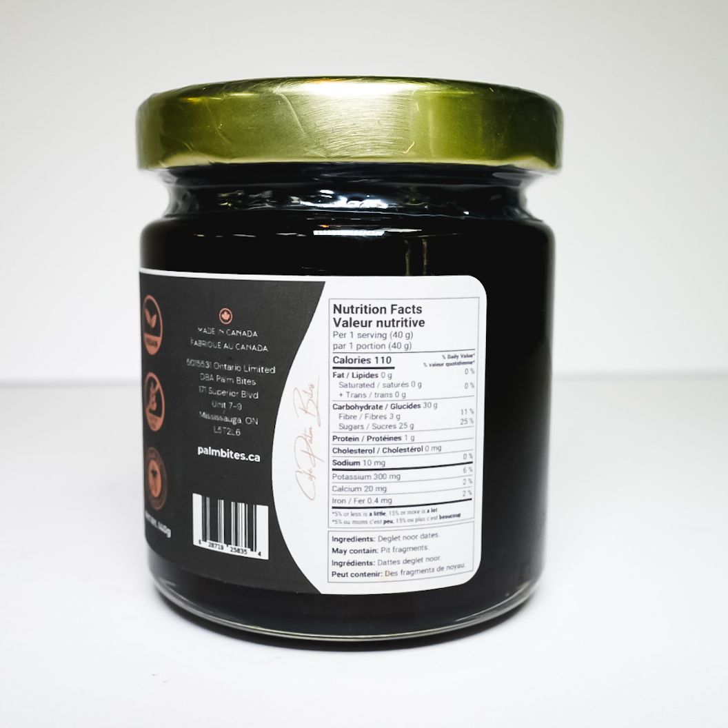 Jar of date syrup with a gold lid and black label on a white background