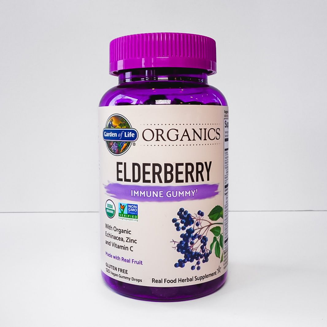 Purple bottle of Organics Elderberry supplement with a magenta cap and white label on a light background